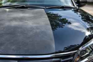 Close-up of a car hood with visibly dull, faded paint next to a glossy reflective section, clear contrast in finish quality, natural daylight, high-detail automotive macro photography style